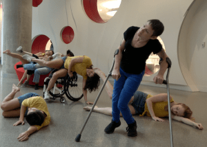 Body Shift Collective dancers on the floor, in a wheelchair, and on crutches
